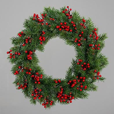 A round fir wreath with vine leaves and red berries on a grey background.