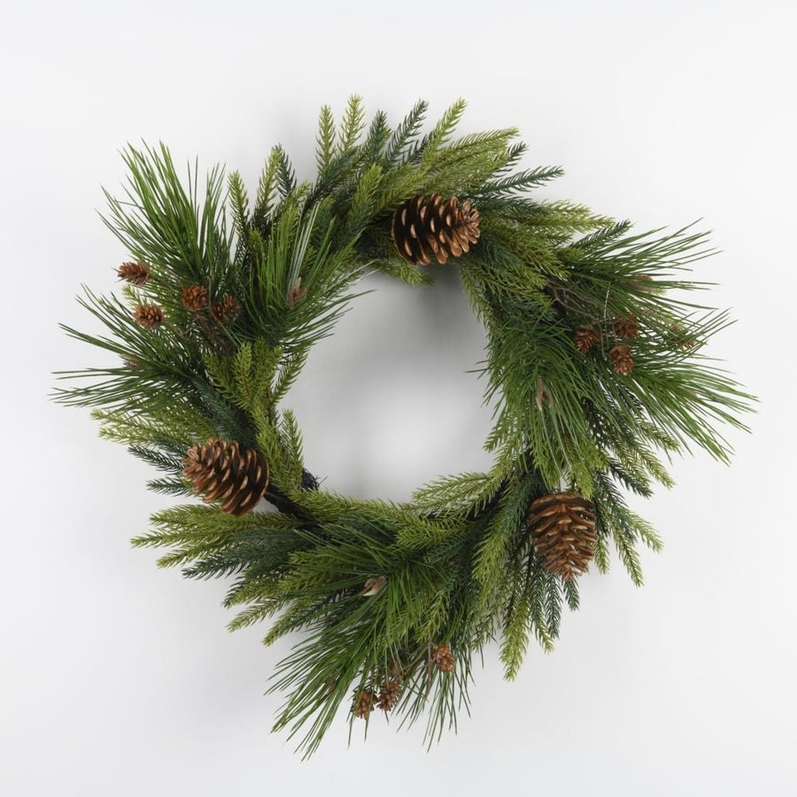 A round green wreath made of pine needles with pine cones, displayed against a white background.