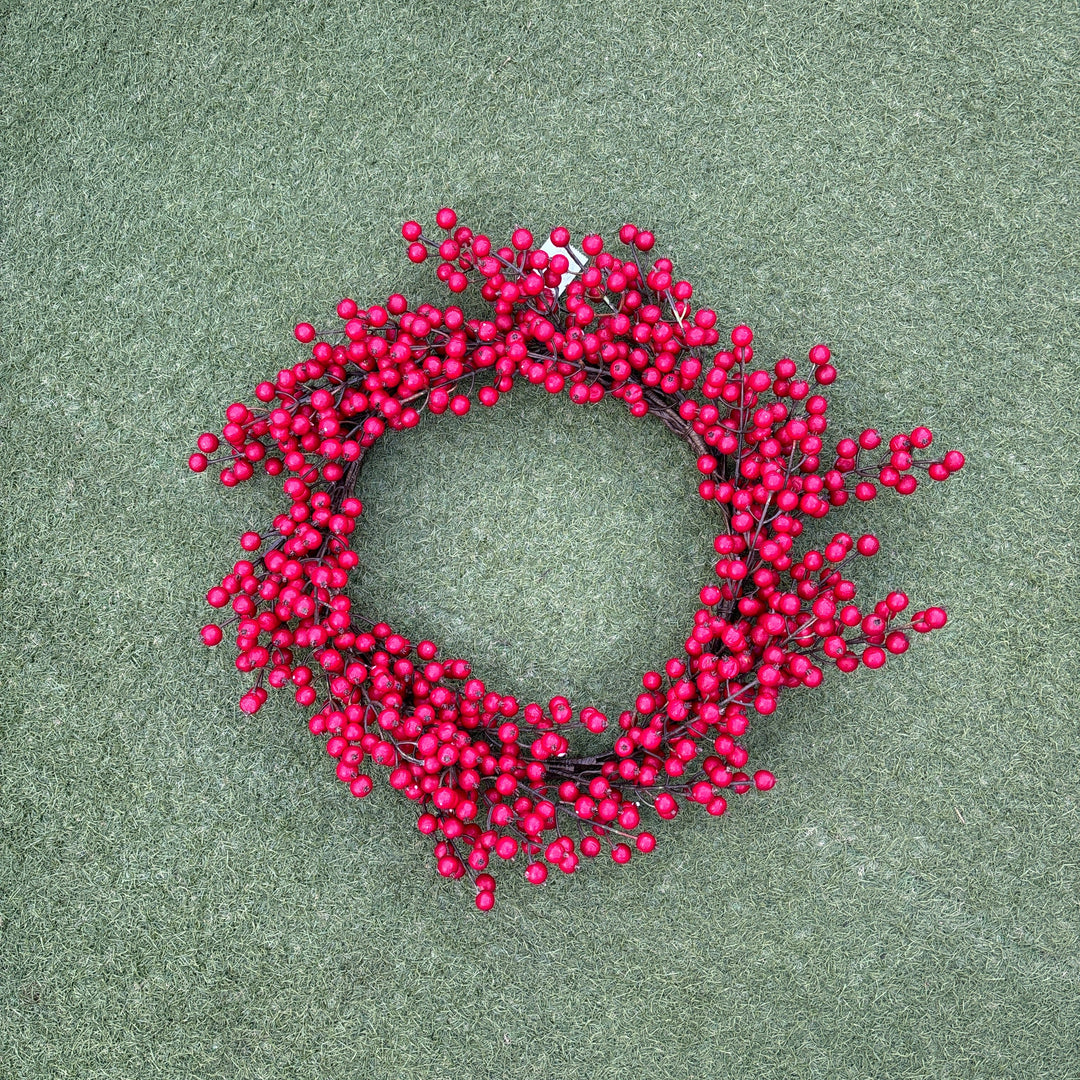 Red berry wreath on a green surface