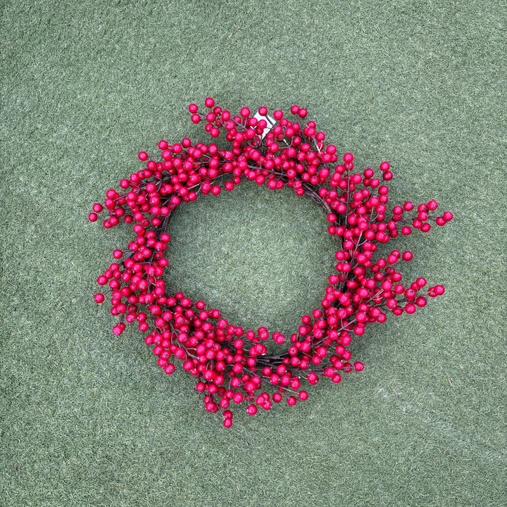 Red berry wreath on a green surface