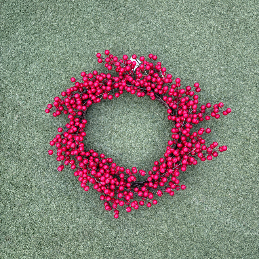 Red berry wreath on a green surface