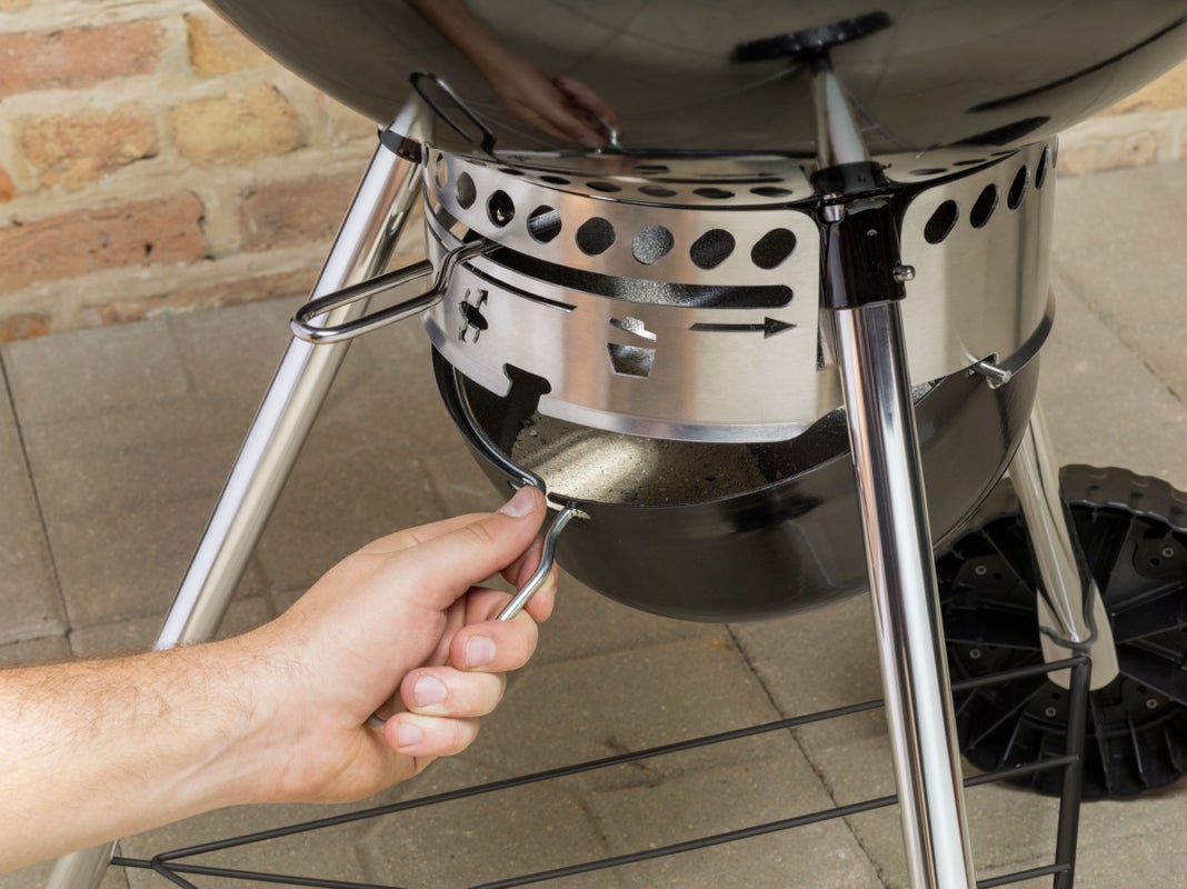 a Hand taking out a Weber Master-Touch E-5750 ash tray
