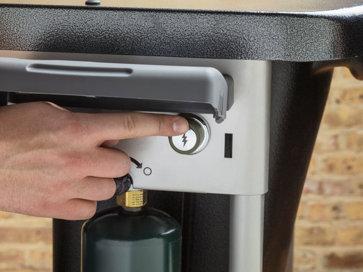 a hand pushing the ignition on a Weber Performer Deluxe
