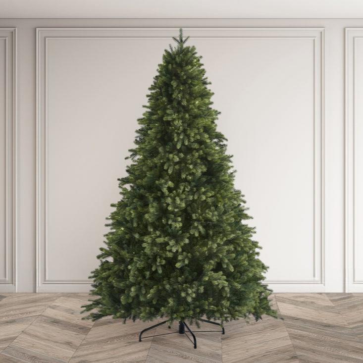 Green artificial Christmas tree on a wooden floor with white paneled walls.