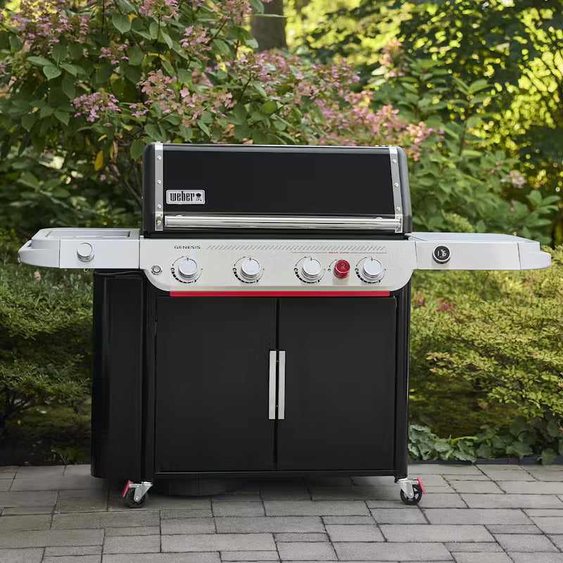 Weber grill on a patio with greenery in the background