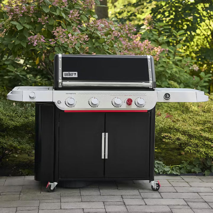 Weber grill on a patio with greenery in the background