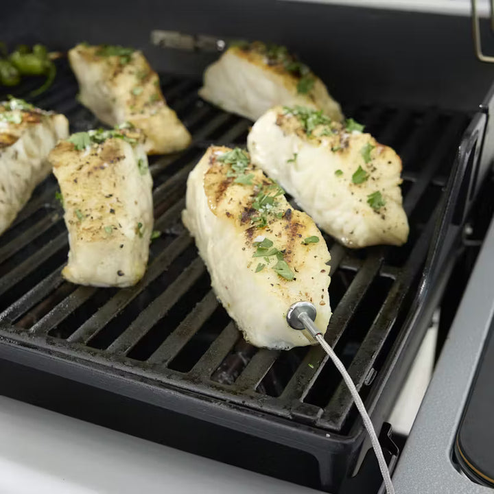 Grilled chicken breasts with herbs on a Weber grill with a thermometer probe.