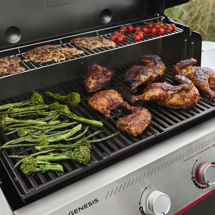 Grill with chicken, vegetables, and other meats cooking on a Weber Genesis brand grill.