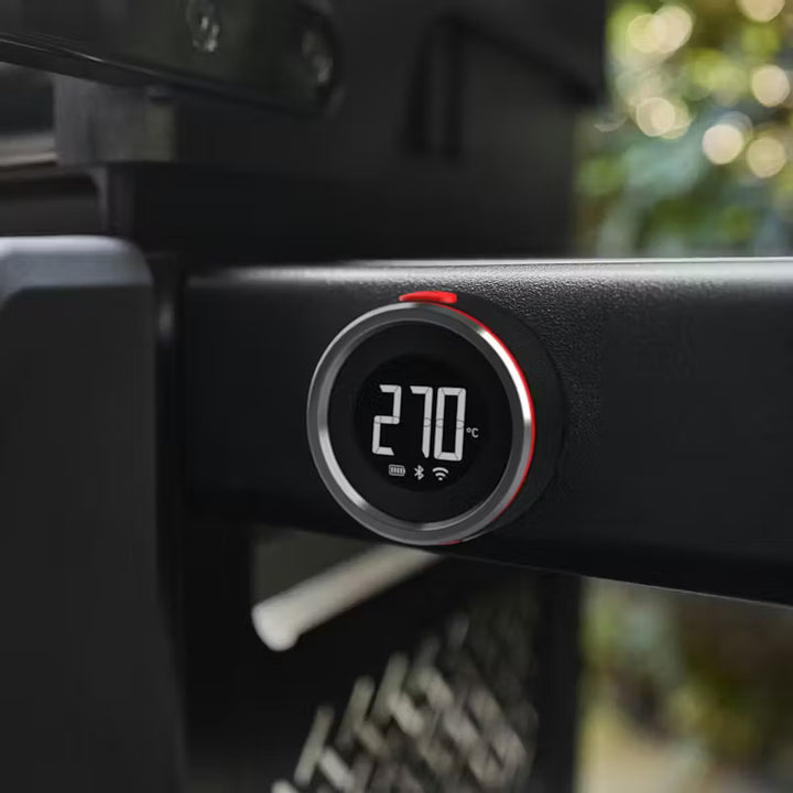Weber Digital temperature controller with a blurred outdoor background