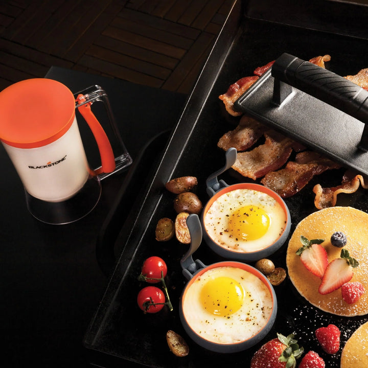 Breakfast spread with eggs, bacon, and a Blackstone mug on a grill.