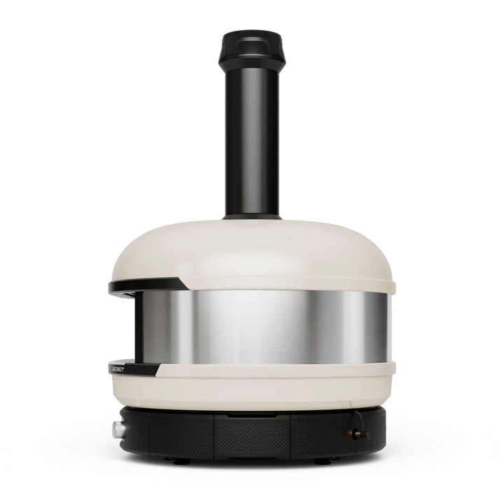 A Gozney Dome pizza oven with a cream-colored ceramic exterior, a brushed stainless steel inner chamber, and a black metal chimney and base, shown against a solid white background.