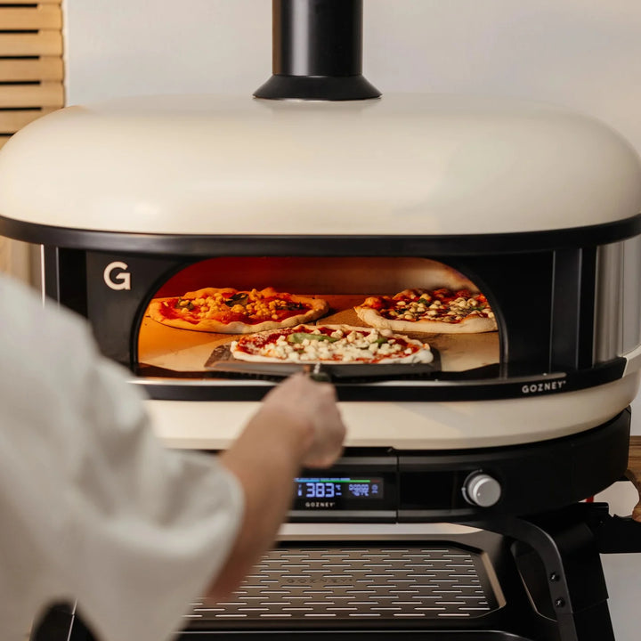 Person placing pizzas into a Gozney pizza oven.