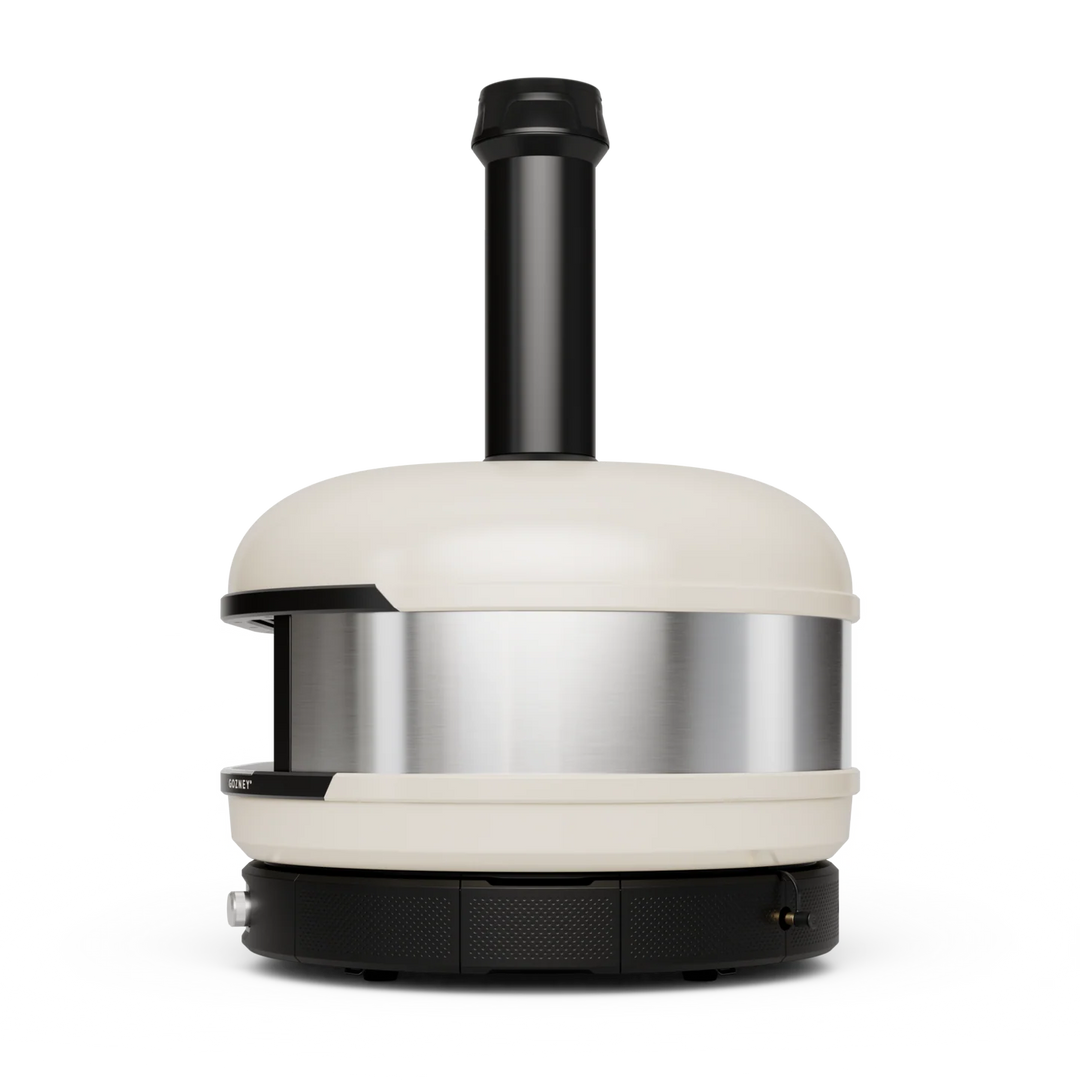 A modern Gozney Dome XL pizza oven with a cream-colored exterior, a brushed stainless steel band around the middle, and a black chimney stack and base, shown on a solid white background.