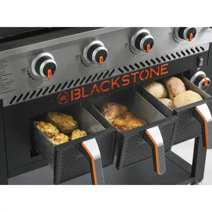 Blackstone grill with food being cooked in its compartments on a white background