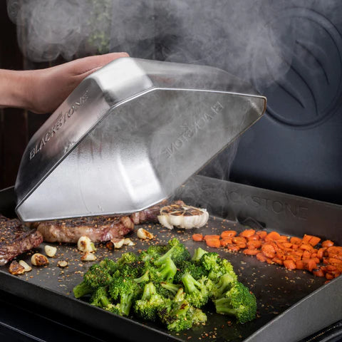 Person using a Blackstone basting dome to cook vegetables on a blackstone griddle